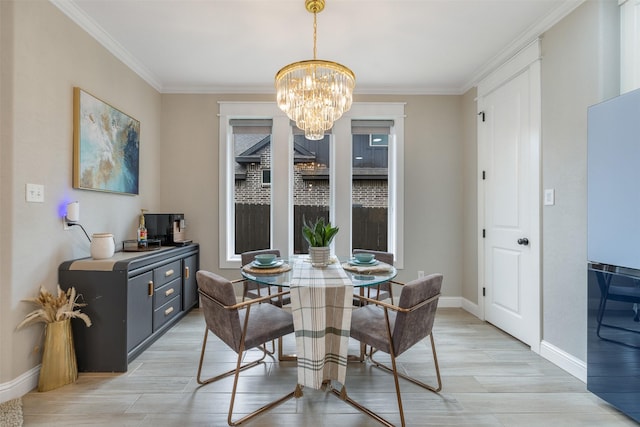 dining space featuring an inviting chandelier, crown molding, light wood-style floors, and baseboards