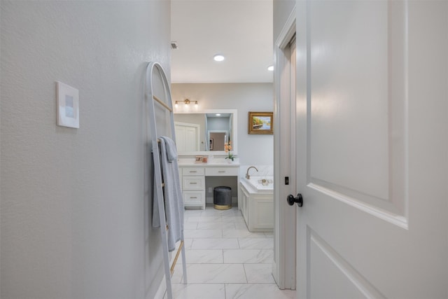 bathroom featuring marble finish floor, a bath, and vanity