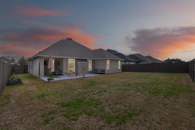 back of property with a yard, a patio area, brick siding, and a fenced backyard