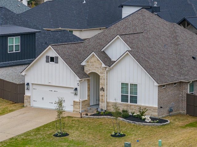 modern farmhouse style home with stone siding, fence, board and batten siding, and a shingled roof