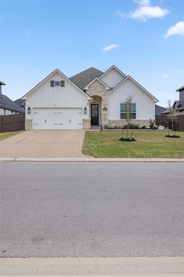 view of front of house with a front lawn, fence, stone siding, and driveway