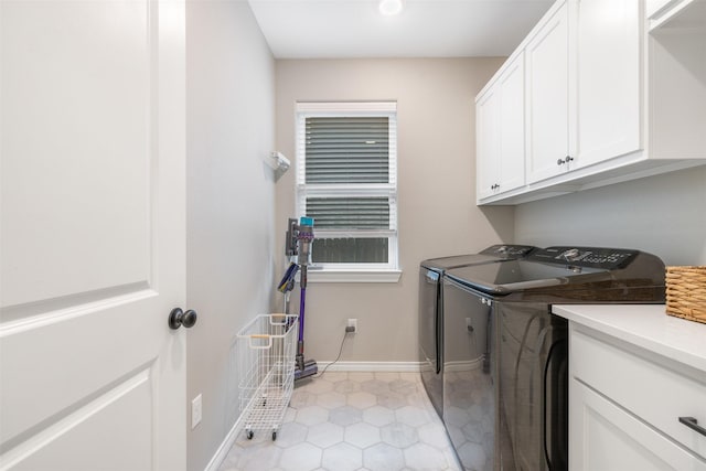 washroom with light tile patterned floors, washing machine and dryer, cabinet space, and baseboards