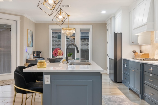 kitchen with visible vents, premium range hood, light countertops, ornamental molding, and a sink