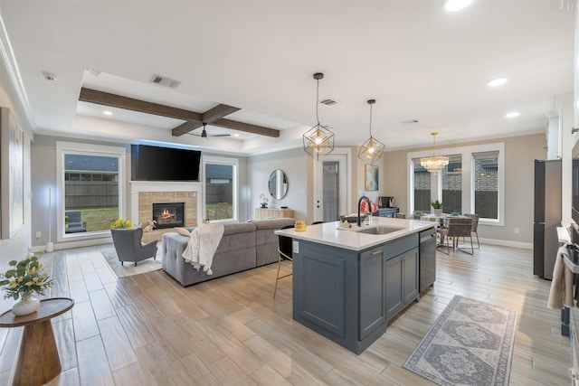 kitchen featuring baseboards, light wood-style flooring, a fireplace, a sink, and light countertops