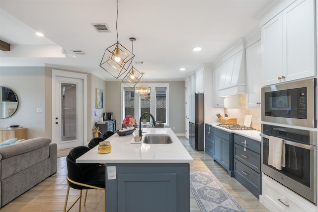 kitchen featuring a breakfast bar, light wood-type flooring, stainless steel appliances, white cabinetry, and a sink