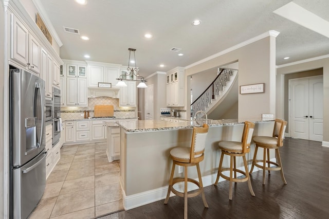 kitchen featuring decorative backsplash, crown molding, visible vents, and appliances with stainless steel finishes