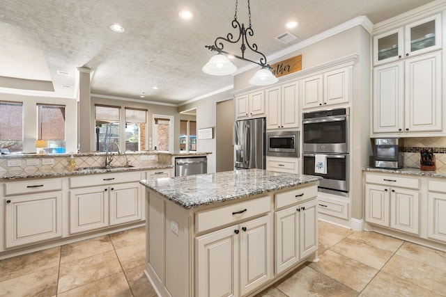 kitchen with visible vents, a kitchen island, decorative backsplash, appliances with stainless steel finishes, and a sink