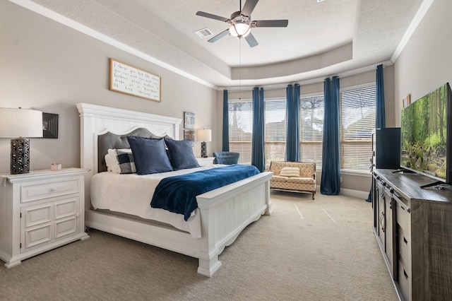 bedroom featuring visible vents, crown molding, baseboards, light colored carpet, and a tray ceiling