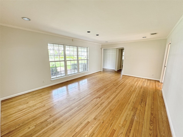 unfurnished room with crown molding, light wood-style floors, baseboards, and visible vents