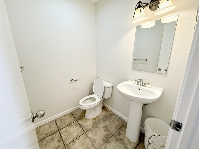 half bathroom featuring tile patterned floors, baseboards, toilet, and a sink