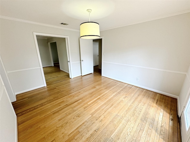 spare room featuring visible vents, crown molding, light wood-type flooring, and baseboards