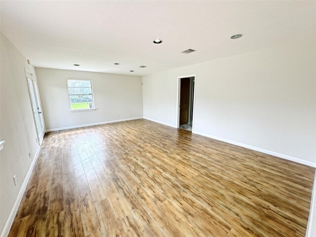 spare room featuring visible vents, recessed lighting, baseboards, and wood finished floors