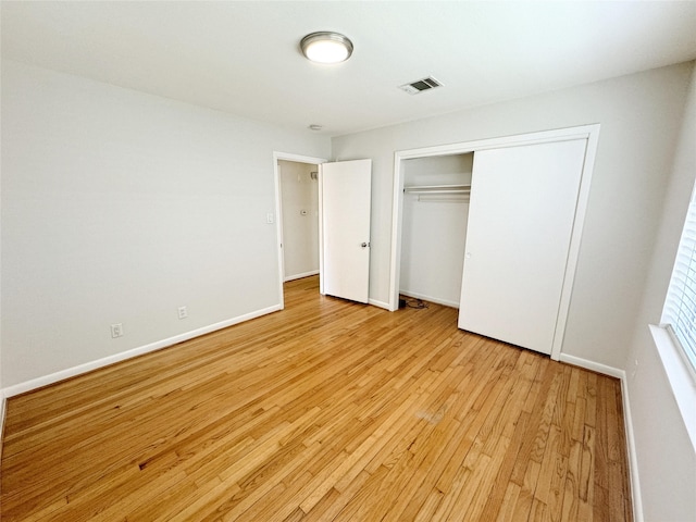 unfurnished bedroom with light wood finished floors, visible vents, a closet, and baseboards