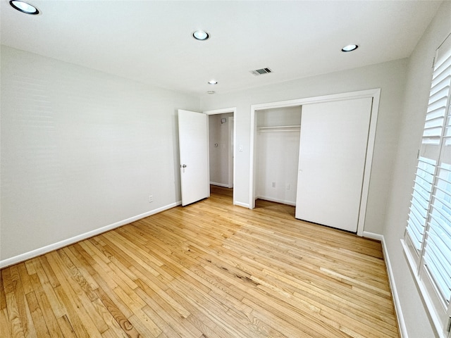 unfurnished bedroom featuring light wood-style flooring, recessed lighting, baseboards, and a closet