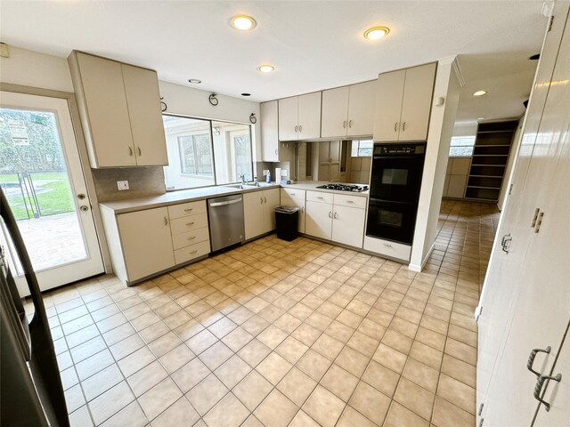 kitchen featuring dobule oven black, gas cooktop, backsplash, stainless steel dishwasher, and light countertops