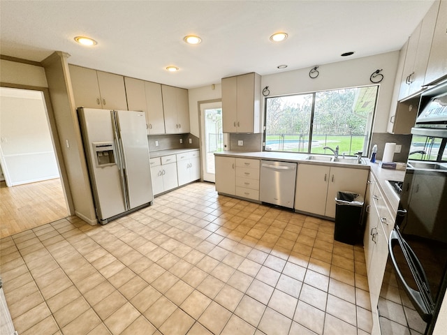 kitchen with a sink, tasteful backsplash, stainless steel dishwasher, white fridge with ice dispenser, and light countertops