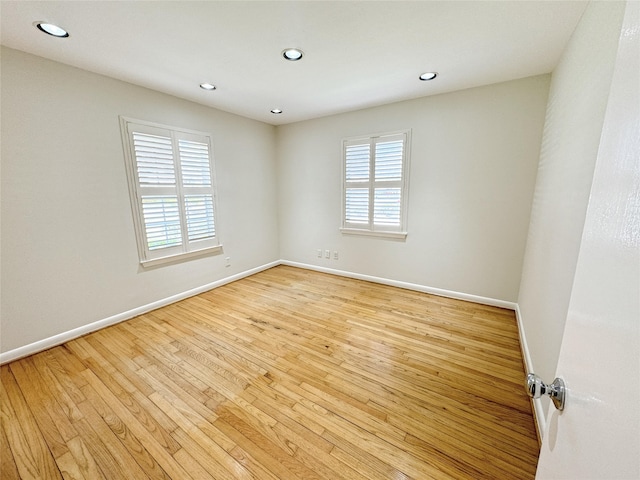 empty room featuring a wealth of natural light, light wood-type flooring, and baseboards