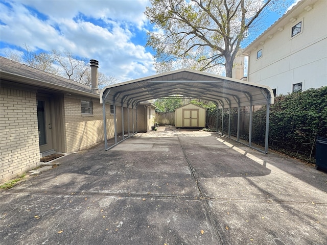 view of vehicle parking with a carport, fence, driveway, and a shed