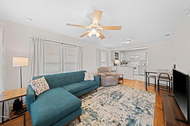 living area featuring light wood-type flooring, visible vents, and ceiling fan