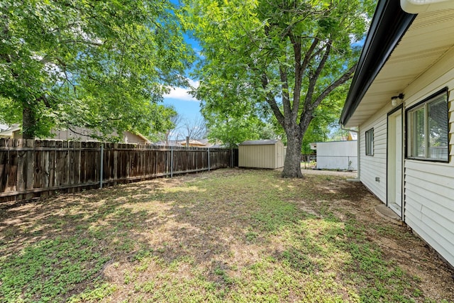 view of yard featuring a storage shed, an outdoor structure, and a fenced backyard