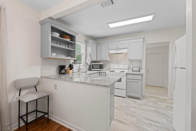 kitchen featuring visible vents, under cabinet range hood, a peninsula, white appliances, and a sink