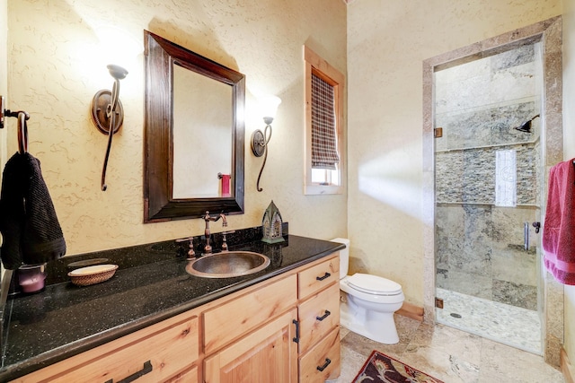 full bathroom with a shower stall, vanity, toilet, and a textured wall