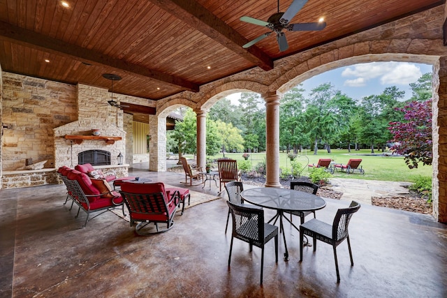 view of patio featuring outdoor dining area, an outdoor stone fireplace, and a ceiling fan