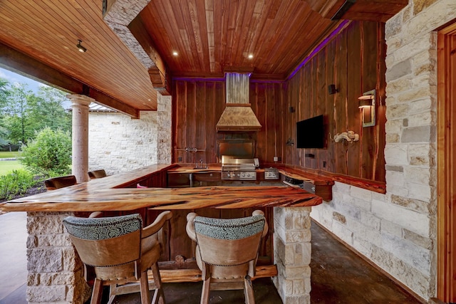 bar featuring custom exhaust hood, wooden ceiling, and ornate columns