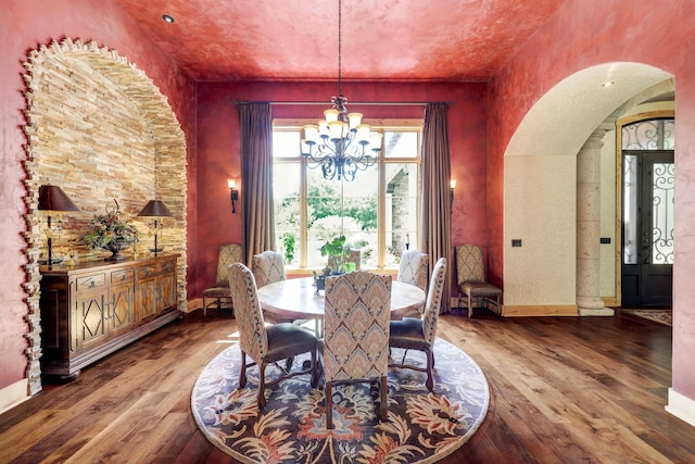 dining room with a notable chandelier, arched walkways, baseboards, and wood-type flooring