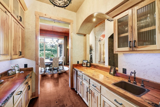 kitchen featuring an inviting chandelier, wood counters, dark wood-type flooring, and a sink