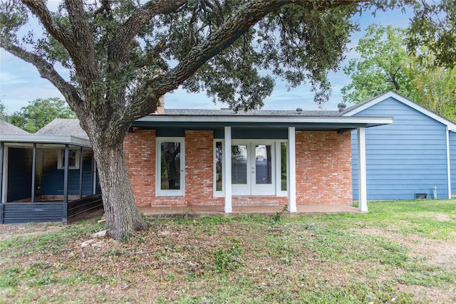 back of property featuring a yard, french doors, brick siding, and a sunroom