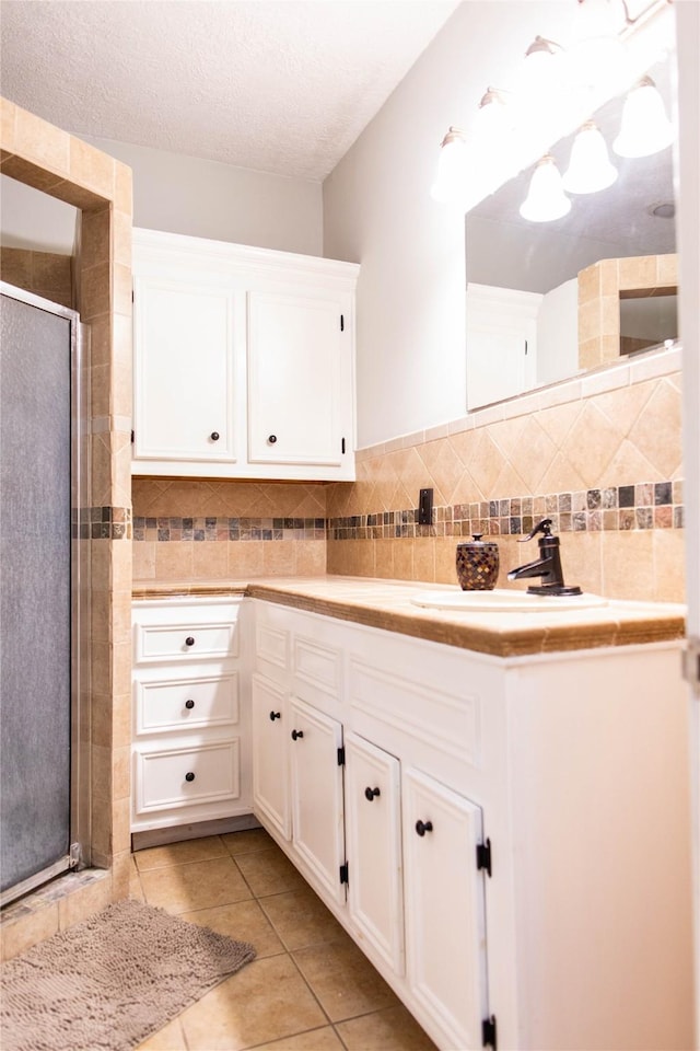 full bath with tile patterned floors, backsplash, a textured ceiling, a shower stall, and vanity