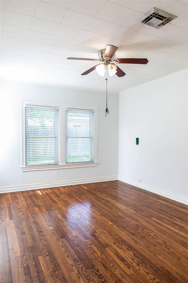 unfurnished room with visible vents, crown molding, baseboards, and wood finished floors