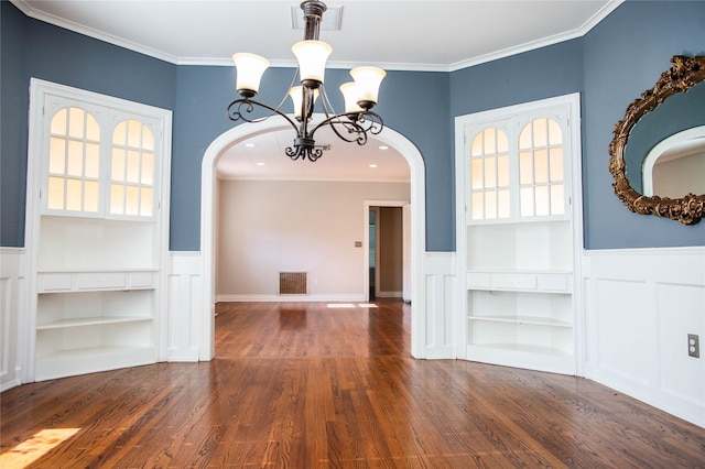 unfurnished dining area featuring visible vents, ornamental molding, wood finished floors, arched walkways, and wainscoting