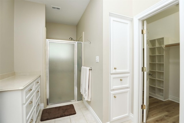 bathroom with tile patterned flooring, baseboards, visible vents, and a stall shower