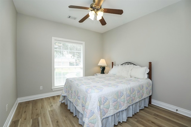 bedroom with visible vents, baseboards, and wood finished floors