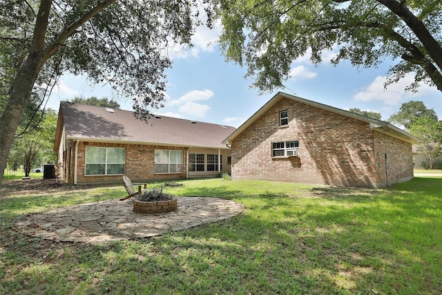 back of property featuring brick siding, a lawn, an outdoor fire pit, and a patio