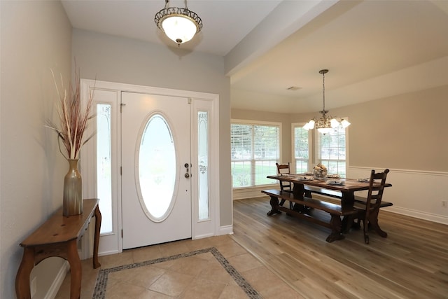 foyer with visible vents, a notable chandelier, light wood-style flooring, wainscoting, and baseboards