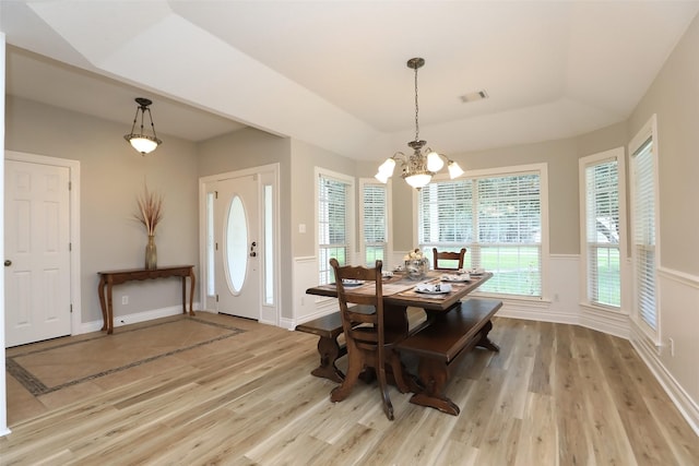 dining area featuring baseboards, visible vents, light wood finished floors, a raised ceiling, and a chandelier