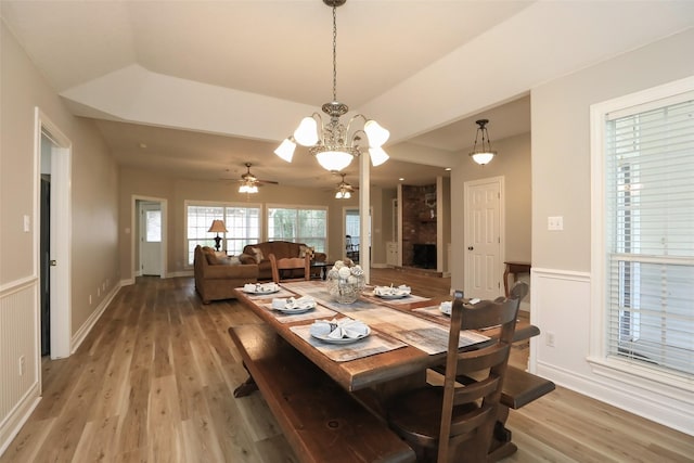 dining space featuring a wainscoted wall, light wood-style floors, a ceiling fan, and a decorative wall