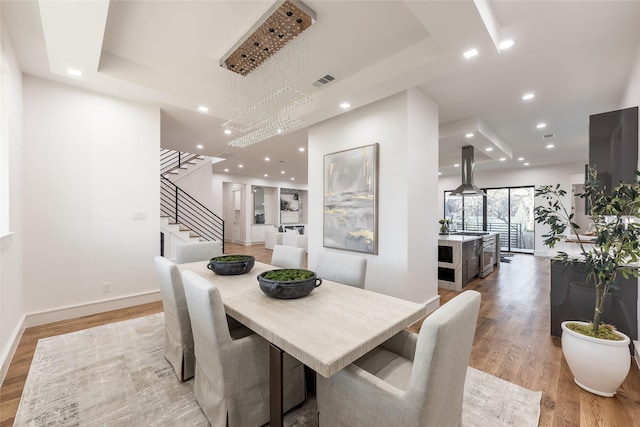 dining area featuring light wood finished floors, visible vents, baseboards, stairway, and recessed lighting