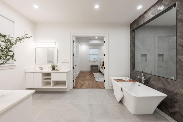 bathroom featuring recessed lighting, a soaking tub, and vanity