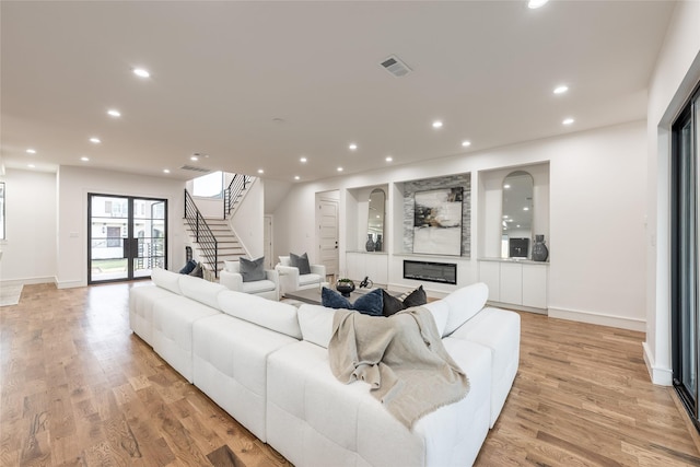 living area with recessed lighting, visible vents, light wood finished floors, and stairway