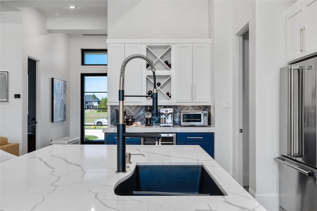 kitchen with decorative backsplash, high end fridge, white cabinets, and a toaster