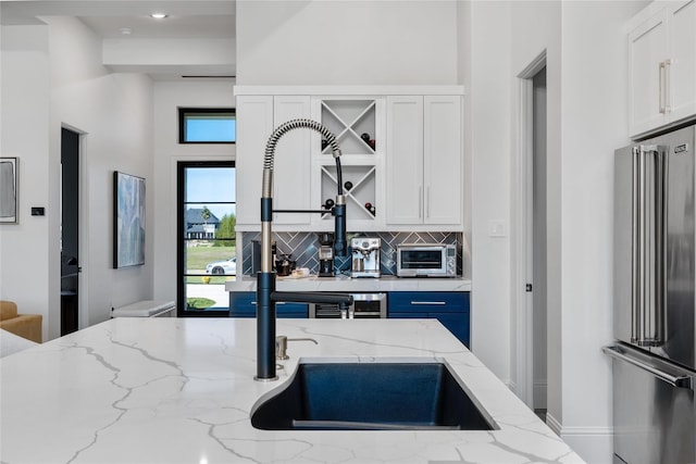 299 Peninsula Point Dr, Montgomery, TX 77356 - kitchen with high quality fridge, white cabinetry, backsplash, and light stone counters