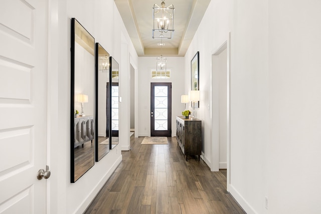 entrance foyer with a tray ceiling, baseboards, a chandelier, and dark wood finished floors