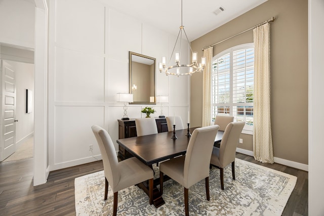 dining room featuring baseboards, visible vents, dark wood finished floors, a decorative wall, and a chandelier