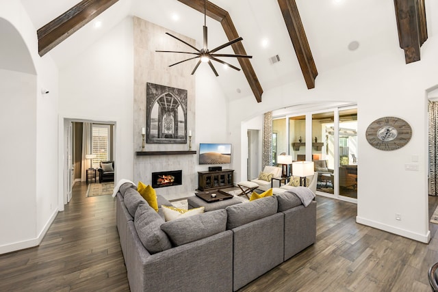 living room featuring a high end fireplace, visible vents, dark wood finished floors, and high vaulted ceiling