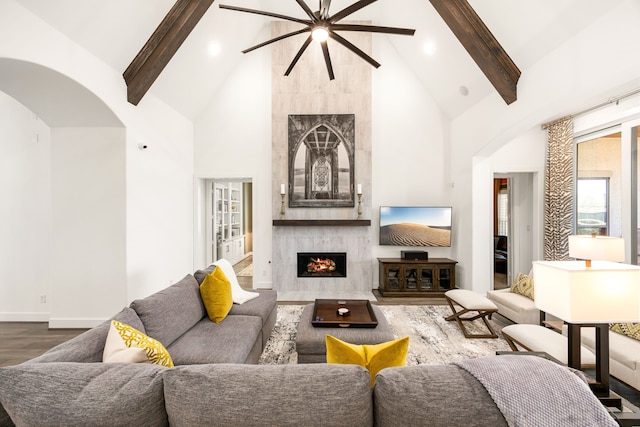 living room with beam ceiling, dark wood-style flooring, high vaulted ceiling, and a premium fireplace