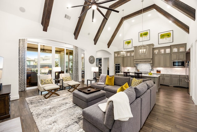 living room with visible vents, dark wood-type flooring, beam ceiling, arched walkways, and high vaulted ceiling